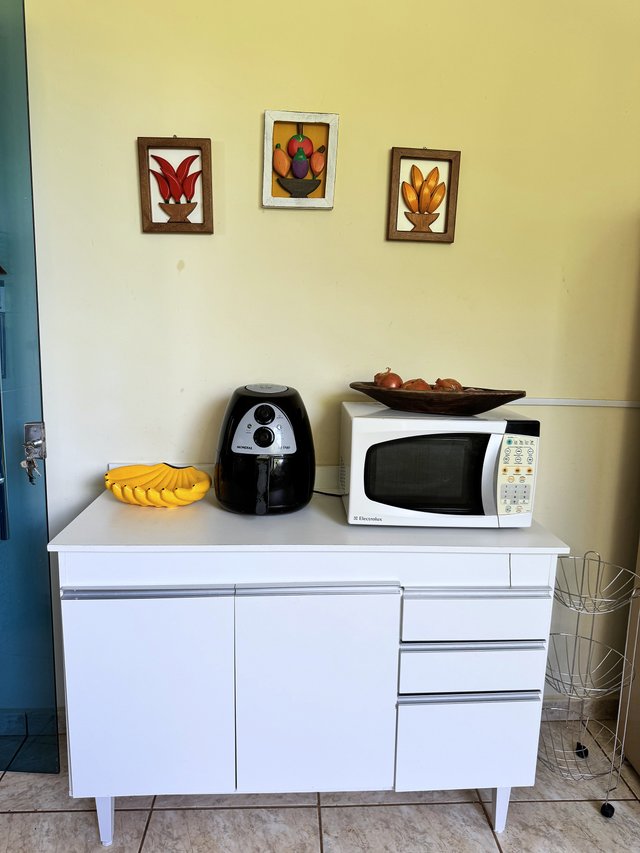 Cozinha — Bancada com fritadeira elétrica, micro-ondas e quadros de frutas