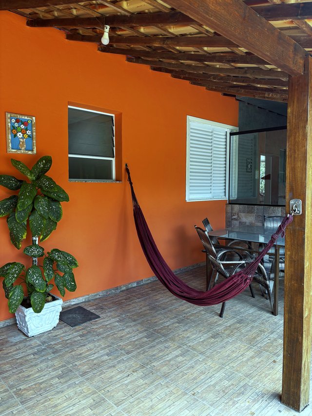 Exterior — Varanda terracota com rede vermelha e plantas