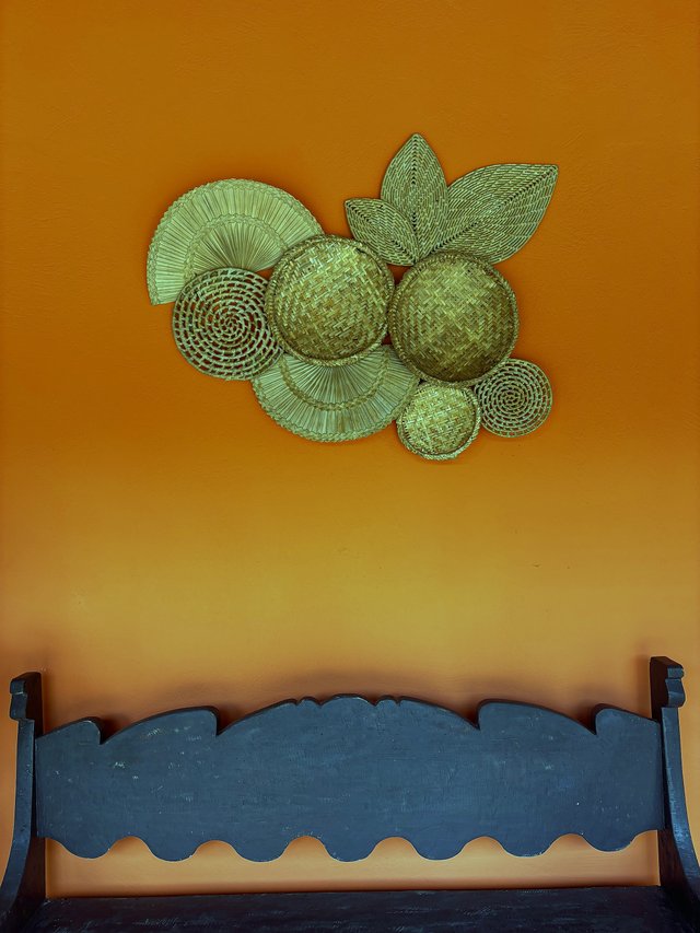 Exterior — Detalhe decorativo com chapéus de palha em parede laranja