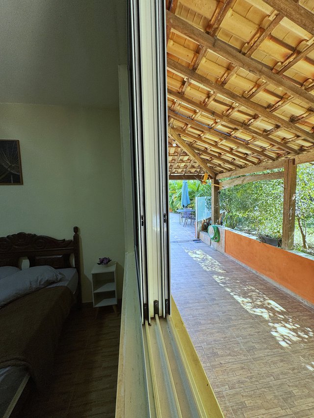 Exterior — Pergolado com trepadeira florida e poltronas