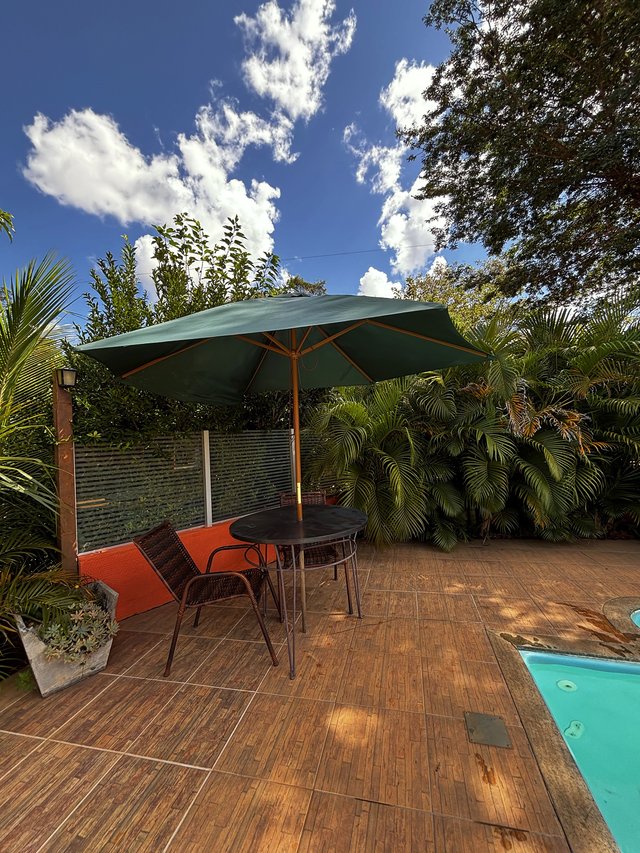 Piscina — Mesa com ombrelone verde e cadeiras de jardim