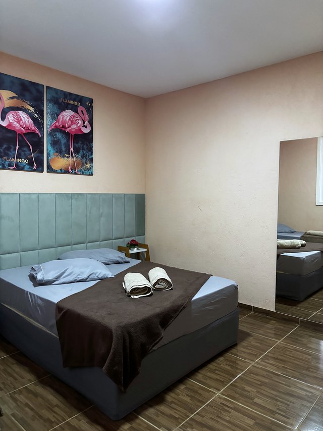 Quarto Flamingo — Cama com toalhas enroladas e flores frescas