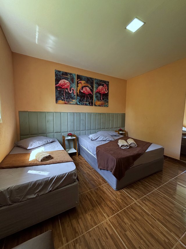 Quarto Flamingo — Vista lateral, com criado-mudo e luminária