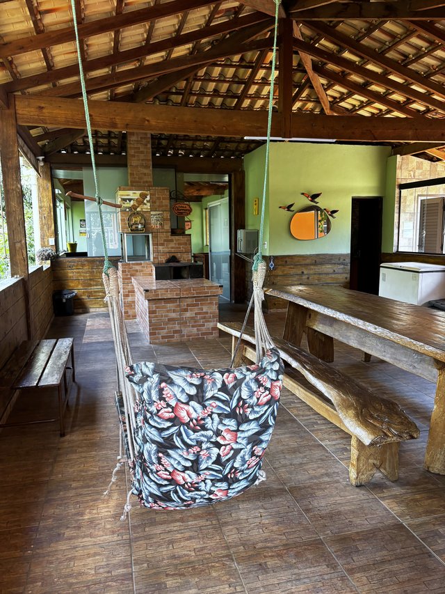 Rancho — Rede de balanço florida no centro do salão com mesa de madeira