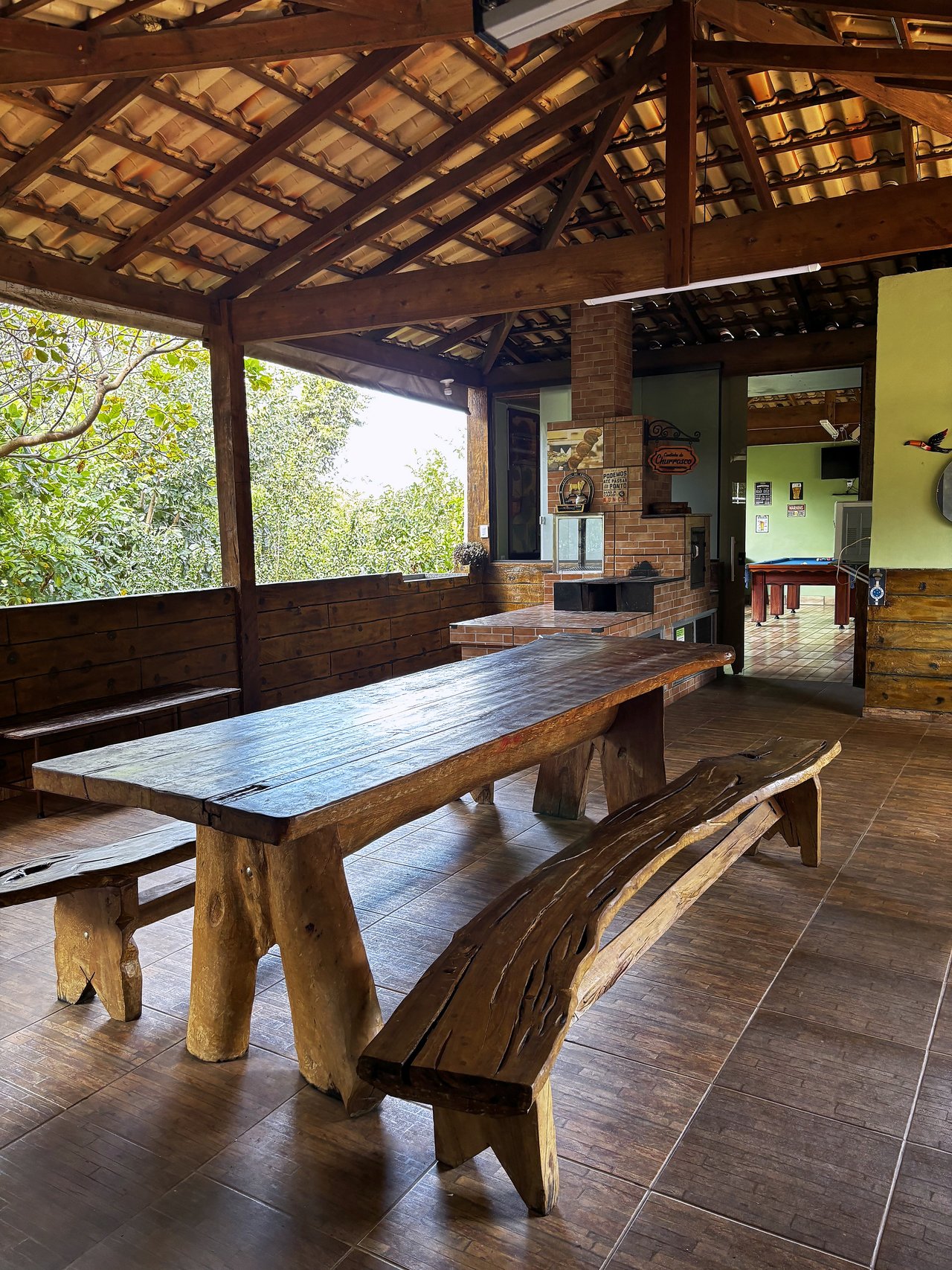 Rancho — Mesa rústica de madeira maciça com bancos longos sob telhado de telhas