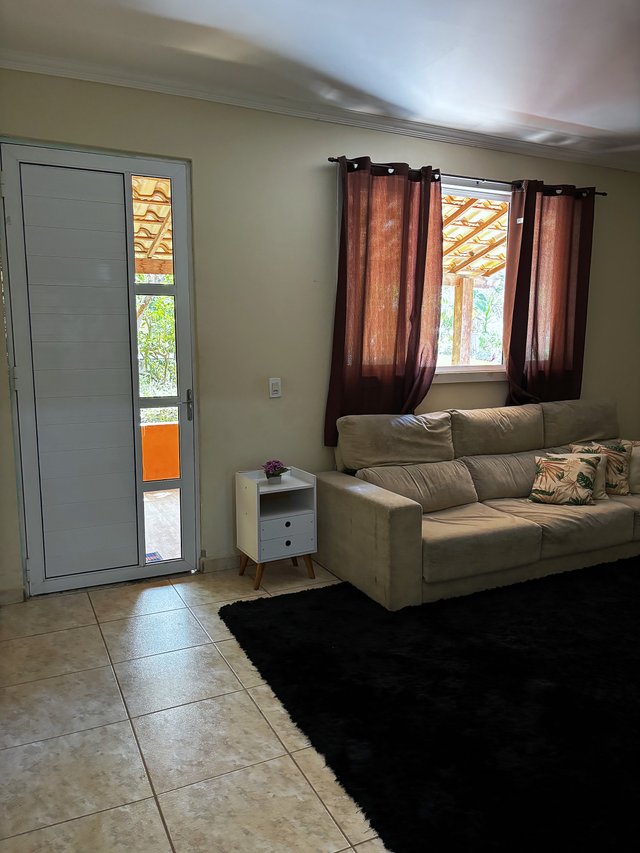 Sala de Estar — Sofá claro com cortina vermelha e porta para o rancho