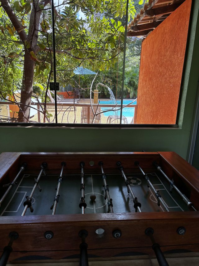 Salão de Jogos — Pebolim em primeiro plano com vista para a piscina