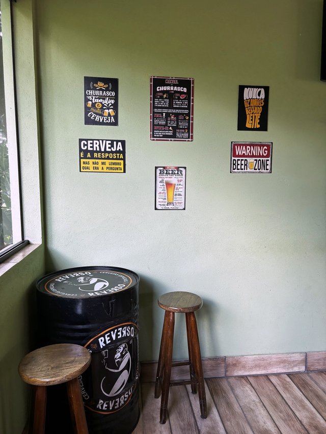 Salão de Jogos — Canto com banquetas, barril decorativo e placas de cerveja