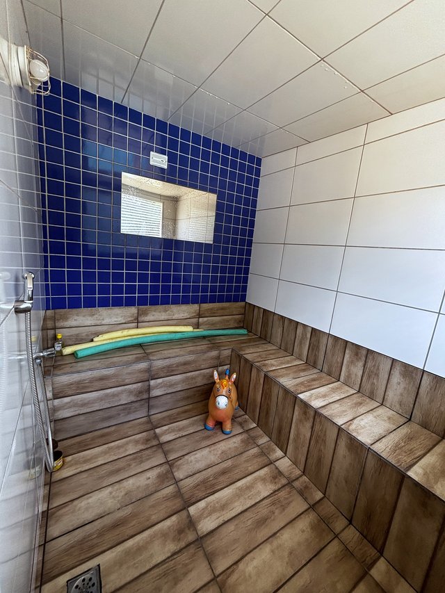 Sauna — Vista do chuveiro com mosaico azul e piso de madeira